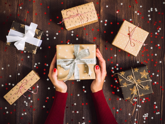 Manos de mujer con caja de regalo de vacaciones de Navidad en mesa festiva decorada