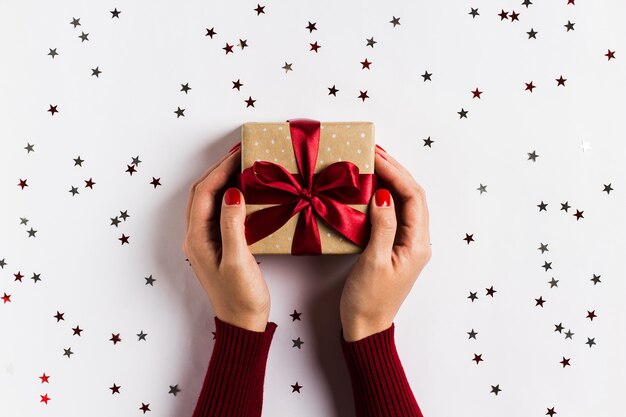 Manos de mujer con caja de regalo de vacaciones de Navidad en mesa festiva decorada