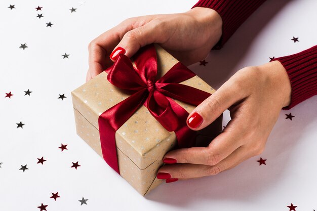 Manos de mujer con caja de regalo de vacaciones de Navidad en mesa festiva decorada