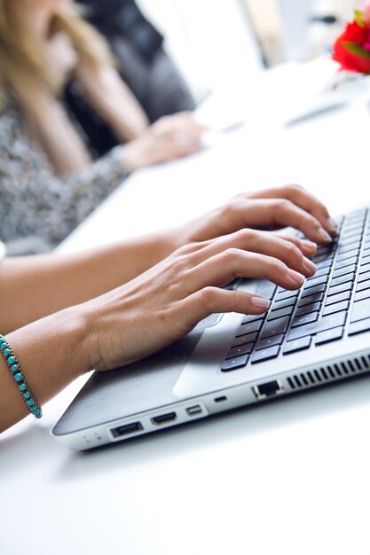 Manos de mujer escribiendo en la computadora portátil