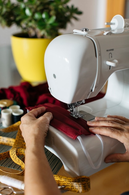 Manos de una mujer haciendo mascarillas de tela con máquina de coser