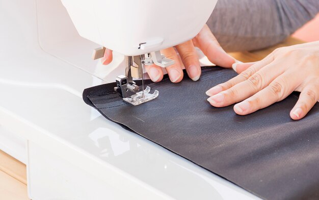 Manos de mujer, haciendo su patchwork usando máquina de coser.