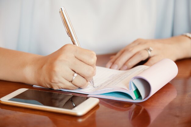 Manos de mujer de negocios escribiendo planes e ideas en el bloc de notas