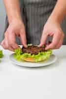 Foto gratuita manos de mujer preparando una hamburguesa