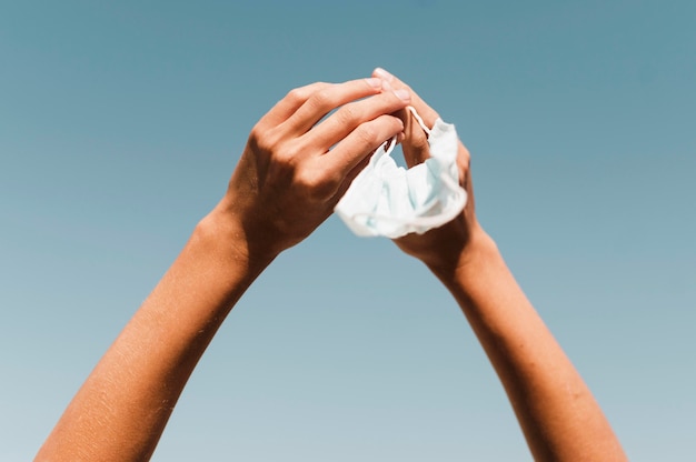 Foto gratuita manos de mujer de primer plano sosteniendo mascarilla