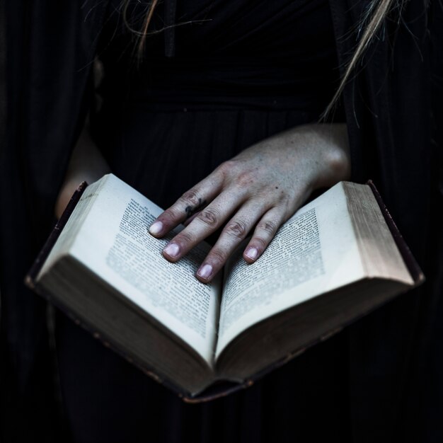 Manos de mujer en ropa negra con libro abierto