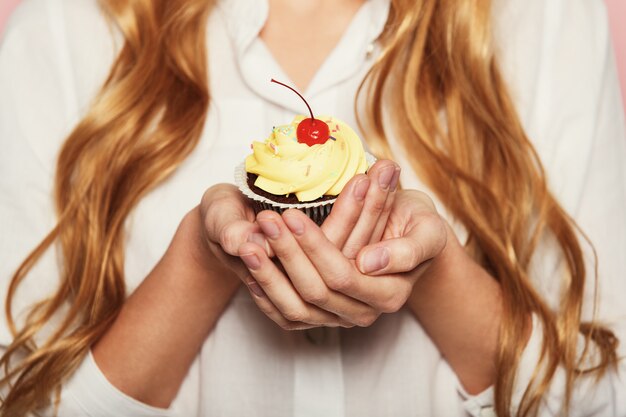 Manos de mujer sosteniendo un delicioso cupcake delicioso