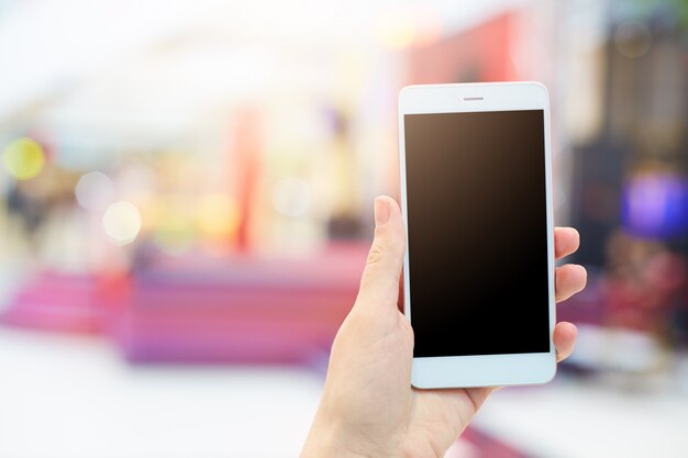 Las manos de la mujer sostiene moderno gadget electrónico. Mujer irreconocible con teléfono móvil blanco