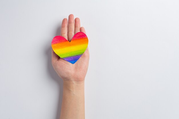 Las manos de la mujer sostienen la conciencia del corazón del arco iris para el concepto de orgullo de la comunidad LGBT