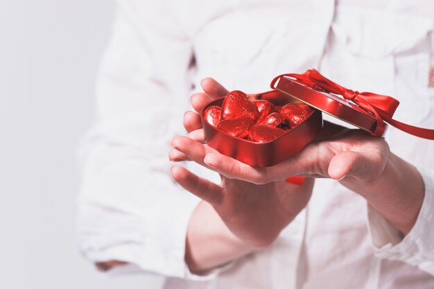 Manos de mujer sujetando una caja con corazones rojos