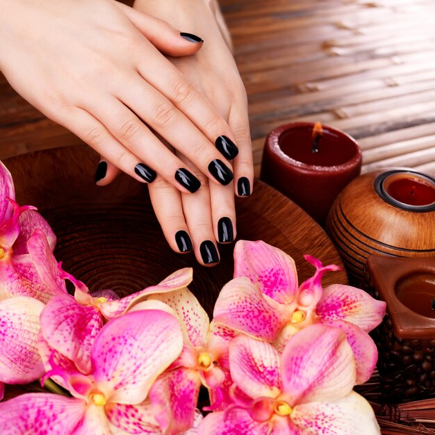 Manos de mujeres hermosas con manicura negra después de los procedimientos de Spa - Concepto de tratamiento de Spa