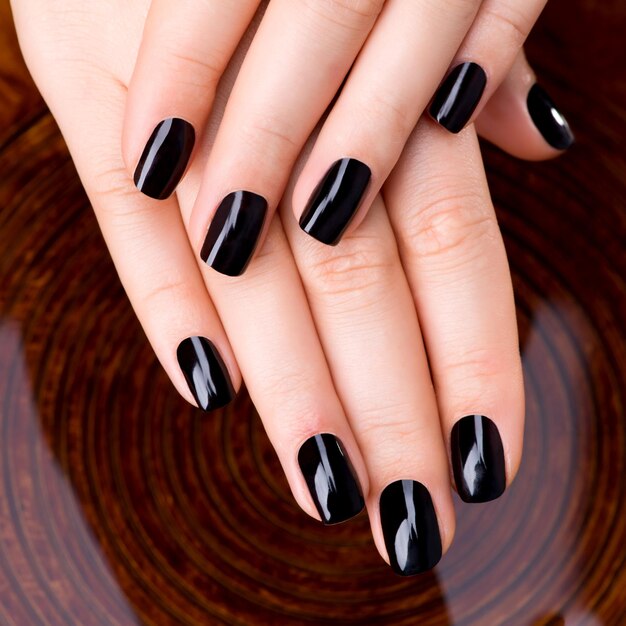 Manos de mujeres hermosas con manicura negra después de los procedimientos de Spa - Concepto de tratamiento de Spa