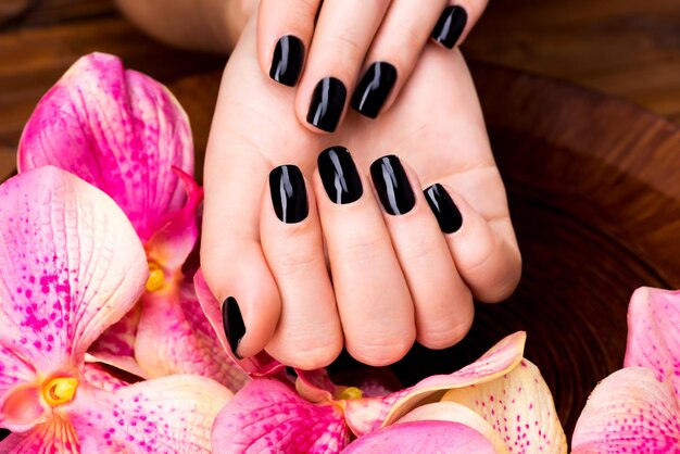 Manos de mujeres hermosas con manicura negra después de los procedimientos de Spa - Concepto de tratamiento de Spa