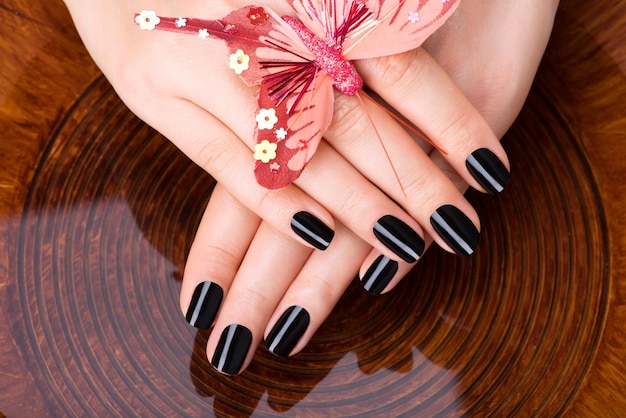 Manos de mujeres hermosas con manicura negra después de los procedimientos de Spa - Concepto de tratamiento de Spa