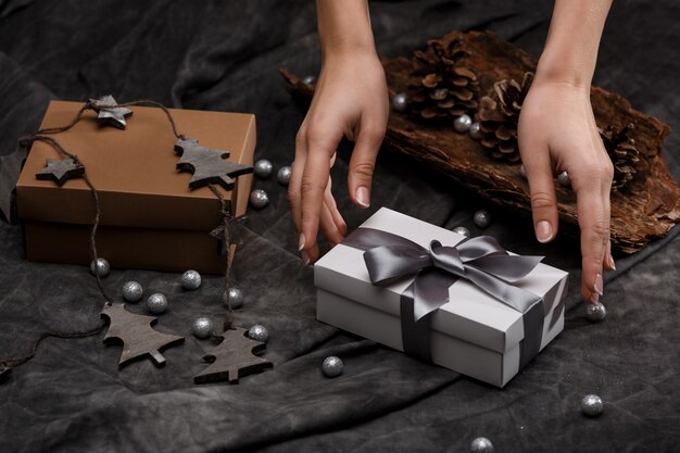 Las manos de la niña ponen la caja de regalo sobre la mesa. Decoración de Navidad de fondo.