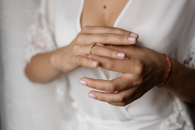 Manos de una novia con un anillo de compromiso con diamantes y una tierna manicura