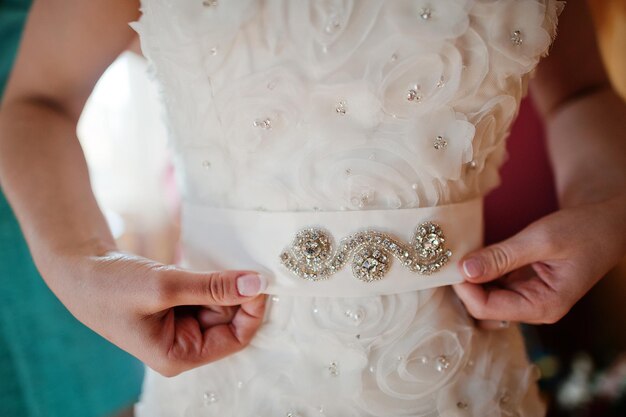 Manos de novia en el cinturón con diamantes