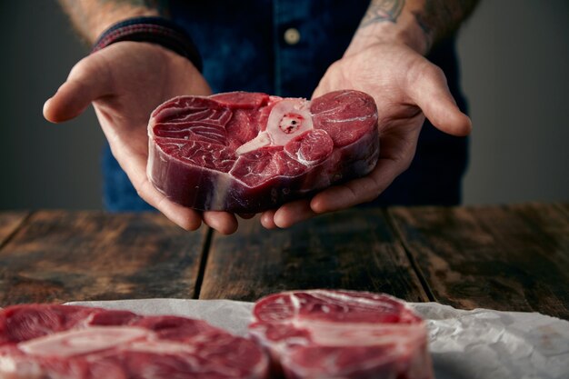 Las manos ofrecen un buen trozo de filete de carne con hueso.