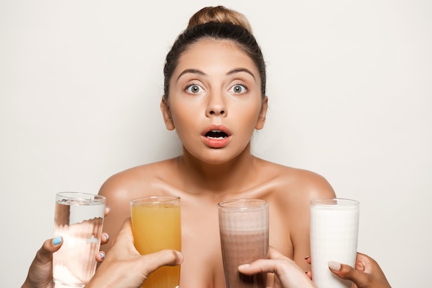 Manos ofreciendo agua, jugo, café o leche a una mujer hermosa