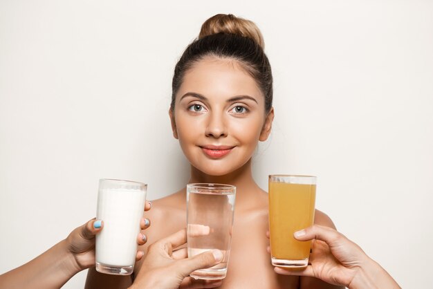 Manos ofreciendo agua, jugo o leche a una mujer hermosa