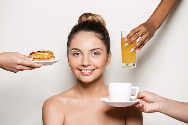 Manos ofreciendo pastel y bebidas a joven bella mujer