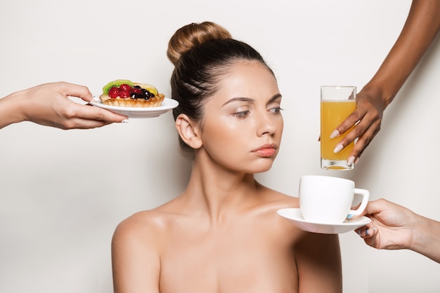 Manos ofreciendo pastel y bebidas a joven bella mujer