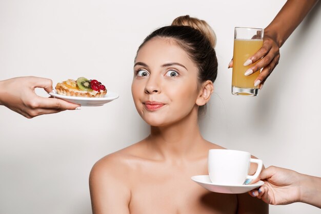 Manos ofreciendo pastel y bebidas a joven bella mujer