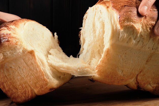 Manos del panadero rompiendo bollos de brioche en bollos de brioche medio dulces Concepto horneado de brioche francés tradicional Enfoque selectivo de primer plano