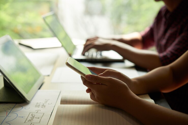 Foto gratuito manos de persona de negocios revisando mensajes en el teléfono inteligente con compañero de trabajo