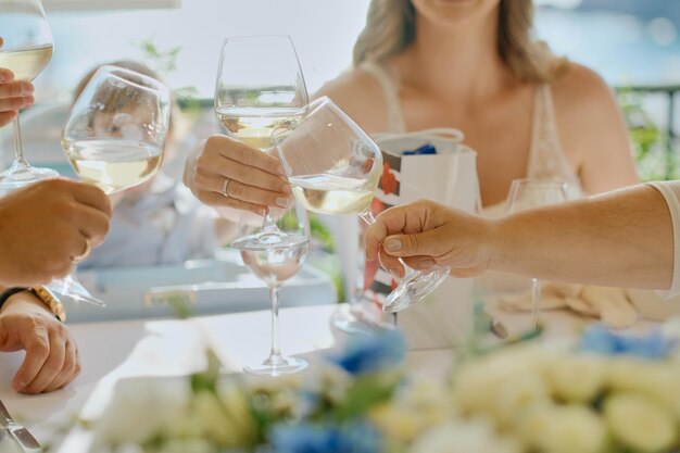 Manos de personas con copas de vino o champán en una mesa en la terraza Reunión de amigos