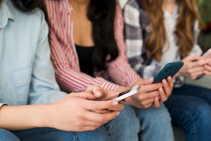 Foto gratuito manos de personas sentadas sosteniendo teléfonos.