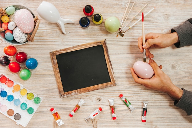 Manos pintando huevo de Pascua en el taller