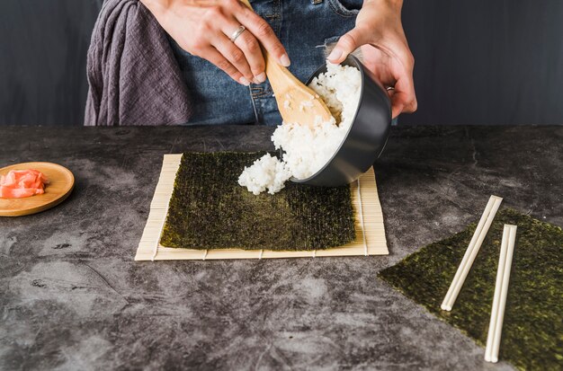 Manos poniendo arroz sobre algas tostadas