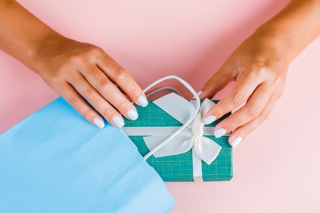 Manos poniendo caja de regalo en bolsa de papel