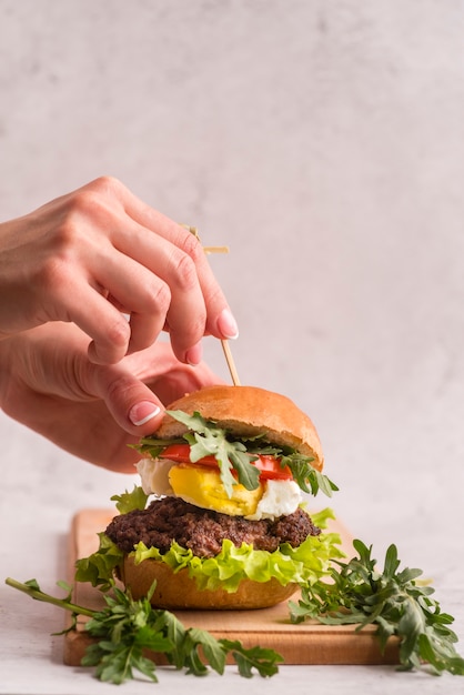 Manos preparando una hamburguesa grande