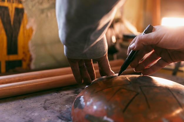 Manos de primer plano dibujando en artículo de metal