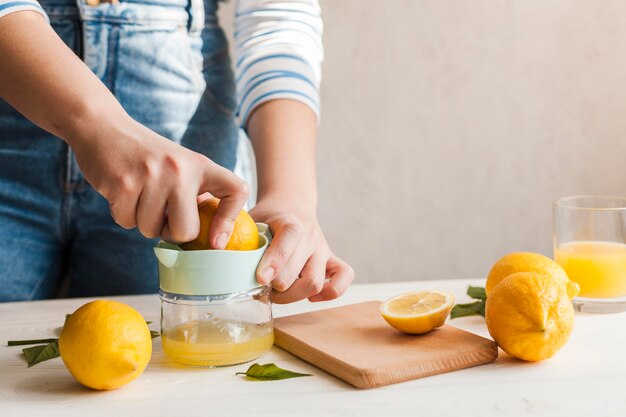 Manos de primer plano haciendo jugo de limón