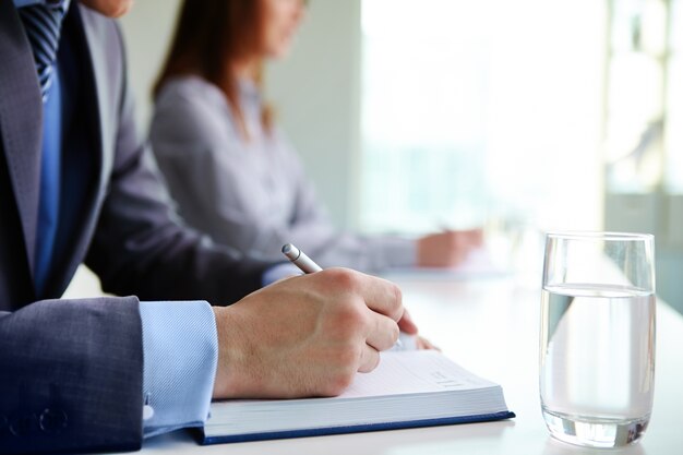 Manos en primer plano de hombre escribiendo en su agenda