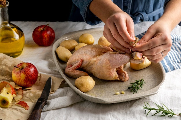 Manos de primer plano preparando pollo y patatas