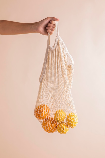 Manos de primer plano sosteniendo bolsa de naranjas