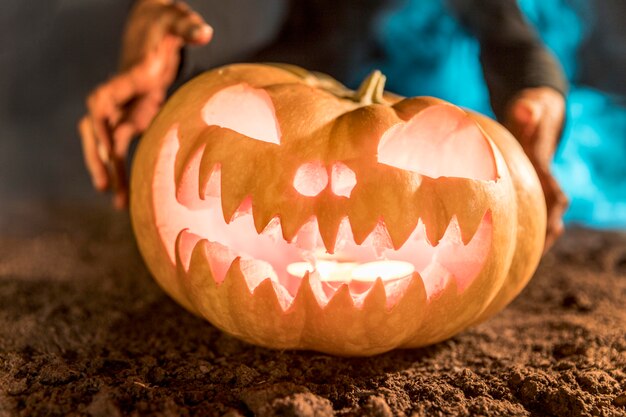 Manos de primer plano sosteniendo calabaza tallada