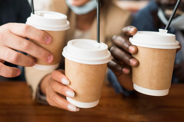 Manos de primer plano sosteniendo tazas de café