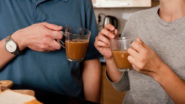 Manos de primer plano sosteniendo tazas de café