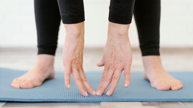 Manos de primer plano tocando la estera de yoga