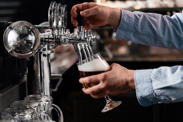 Foto gratuita manos de primer plano vertiendo cerveza en vidrio