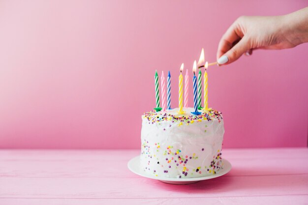 Manos que encienden velas en la torta