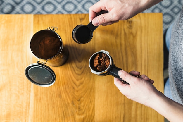 Manos que llenan el filtro con café en polvo