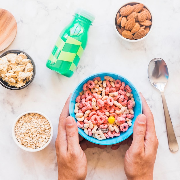 Foto gratuita manos que sostienen un tazón azul con cereal