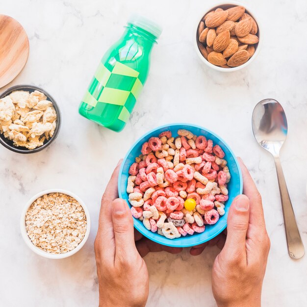 Manos que sostienen un tazón azul con cereal