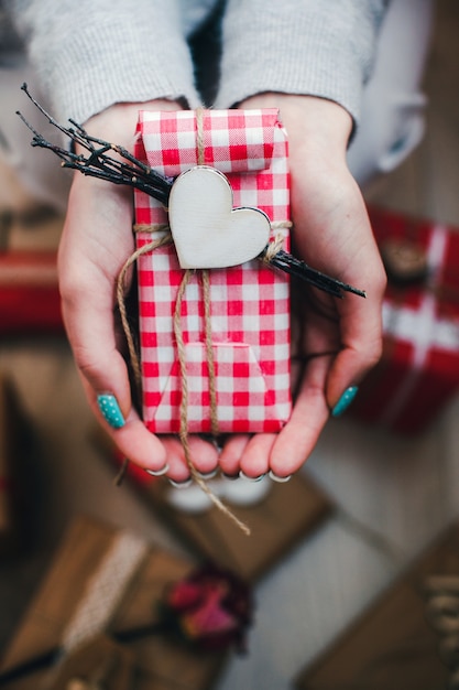 Foto gratuita manos con un regalo rojo y blanco con un corazón